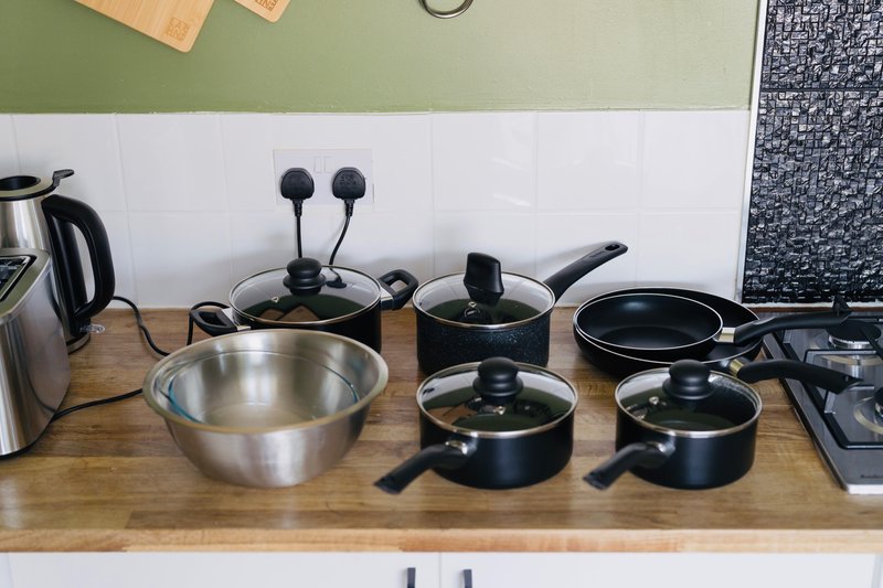 Kitchen counter with cookware set, kettle, and small appliances on wooden surface