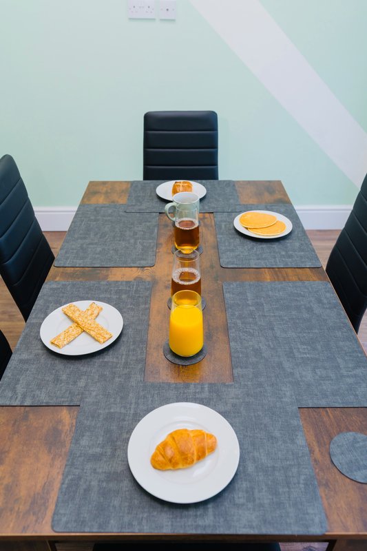 Dining table set with plates, croissants, orange juice and beverages