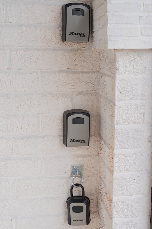 Exterior wall with three mounted key storage boxes branded Master Lock