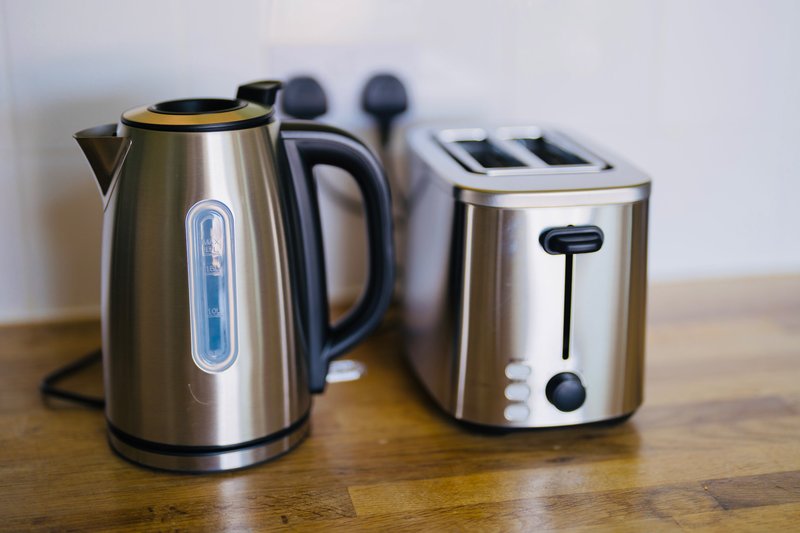 Stainless steel electric kettle and toaster on wooden countertop