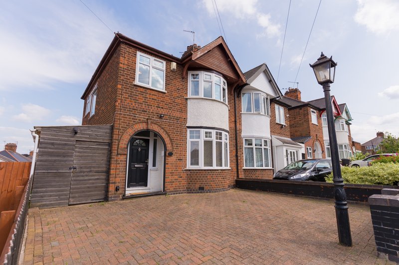 Semi-detached brick house with driveway, garage, and front garden