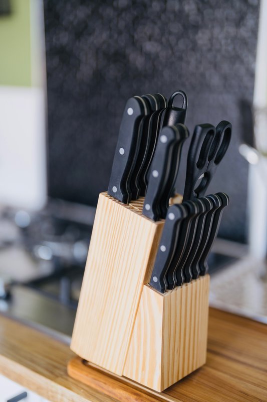 Wooden knife block with black-handled kitchen knives on countertop