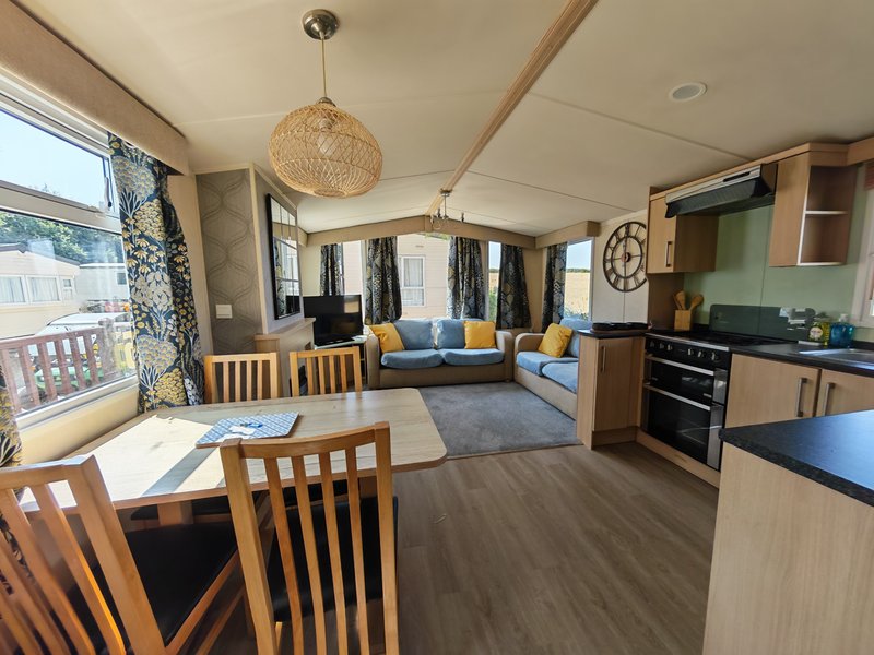 Open-plan living space with kitchen, dining area, and lounge with colorful cushions