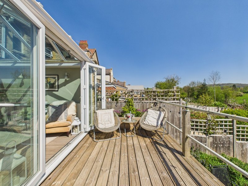 Wooden deck with two wicker chairs, railing, and countryside view