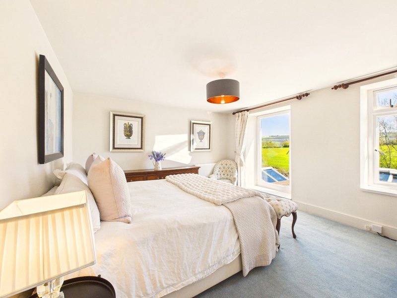 Bright bedroom with twin beds, framed wall art, pendant light and countryside views
