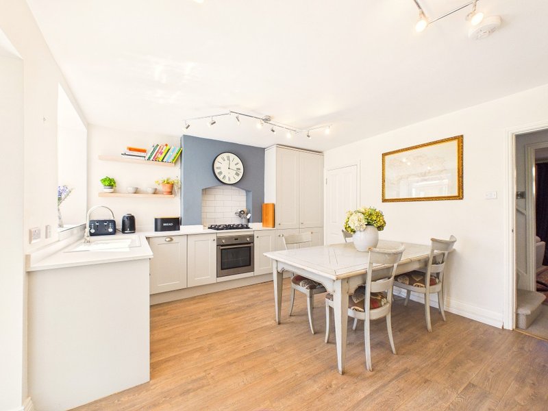 Open-plan kitchen and dining area with cream cabinetry, wooden floor, and white dining table with chairs