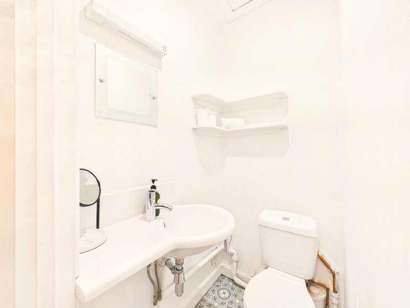 Clean bathroom with white sink, toilet, mirror and storage shelves