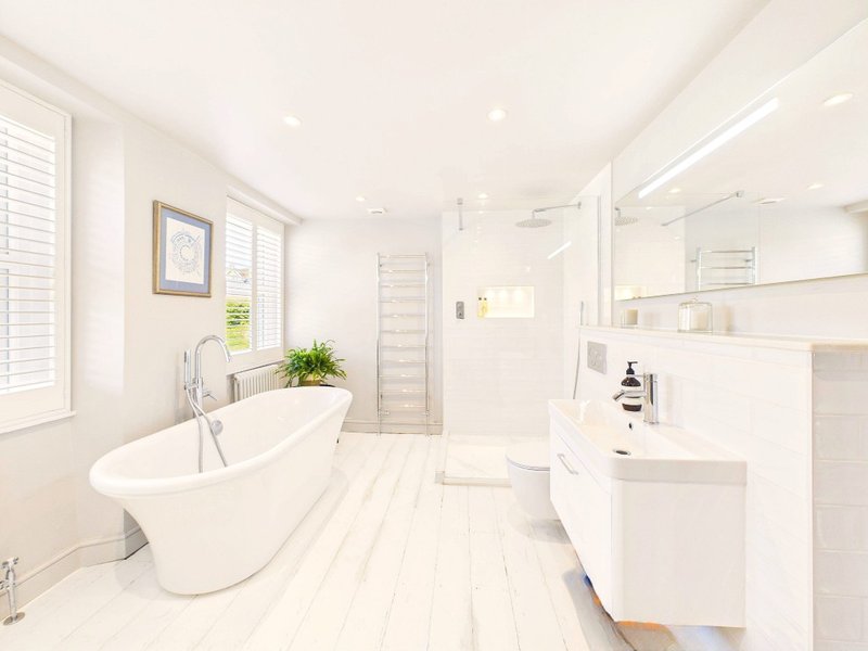 Bright modern bathroom with freestanding white bathtub, dual vanity, walk-in shower and windows