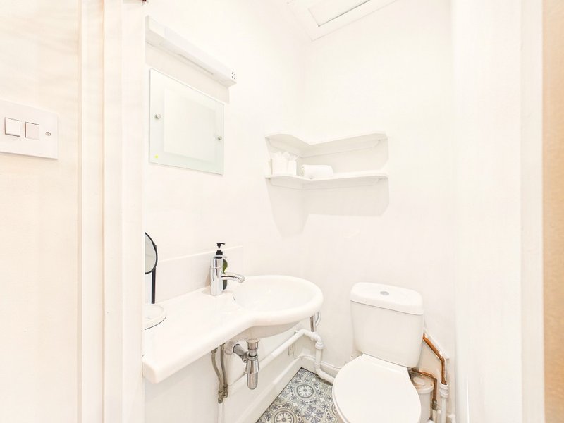 Clean white bathroom with sink, toilet, mirror and wall-mounted shelves