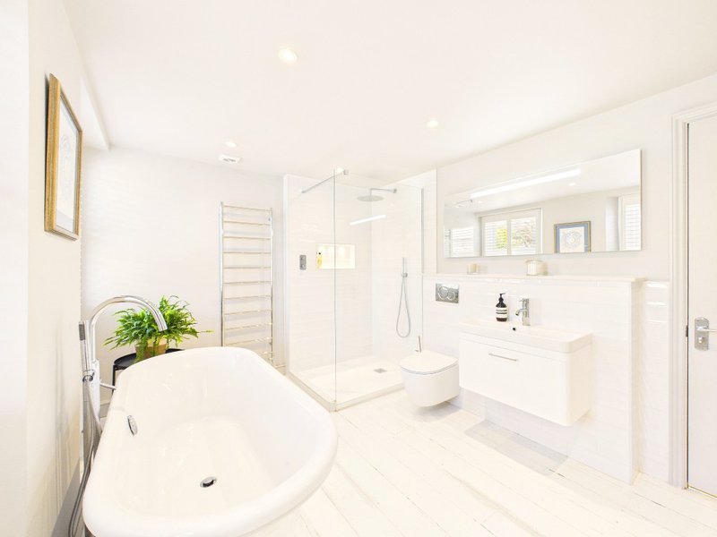 Spacious modern bathroom with freestanding bathtub, walk-in shower, double vanity and potted plant