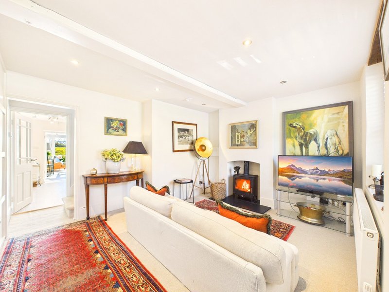 Bright living room with cream sofa, fireplace, artwork, wooden desk and red patterned rug.