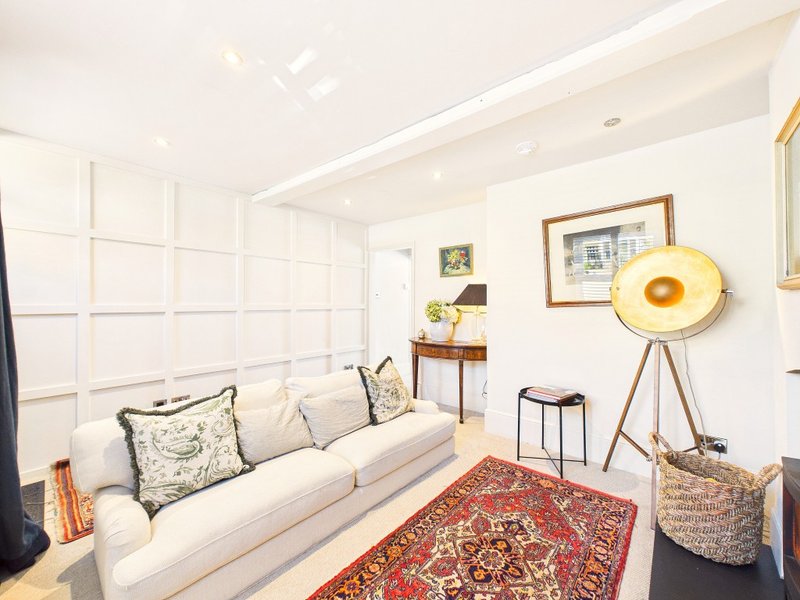 Bright living room with cream sofa, decorative cushions, red rug, and yellow floor lamp