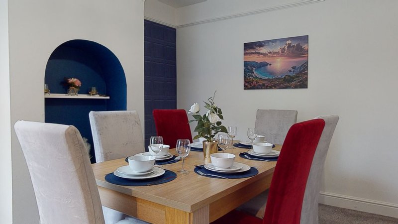 Dining room with wooden table, upholstered chairs, place settings, and blue architectural niche
