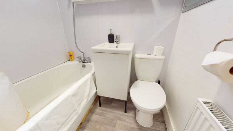 Clean bathroom with bathtub, toilet, sink, mirror and wooden floor