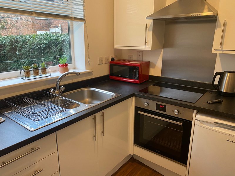 Modern kitchen with cream cabinets, black countertop, stainless steel appliances and window