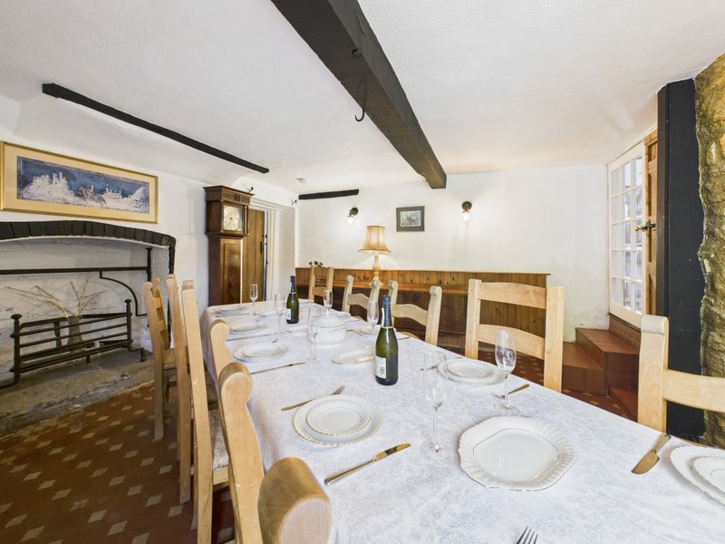 Dining room with wooden table set for meal, chairs, fireplace, and framed artwork on walls