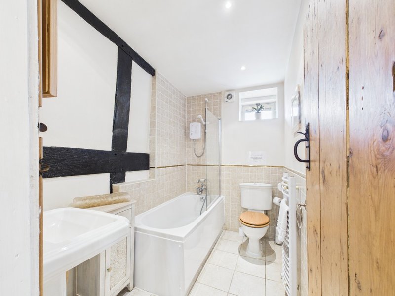 Modern bathroom with white subway tiles, bathtub, toilet, sink, and wooden door frame