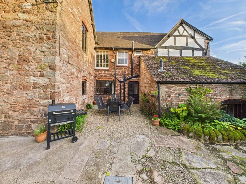 Exterior courtyard with brick buildings, BBQ grill, seating area and potted plants