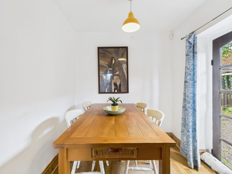 Dining room with wooden table, white chairs, pendant light, and framed wall art