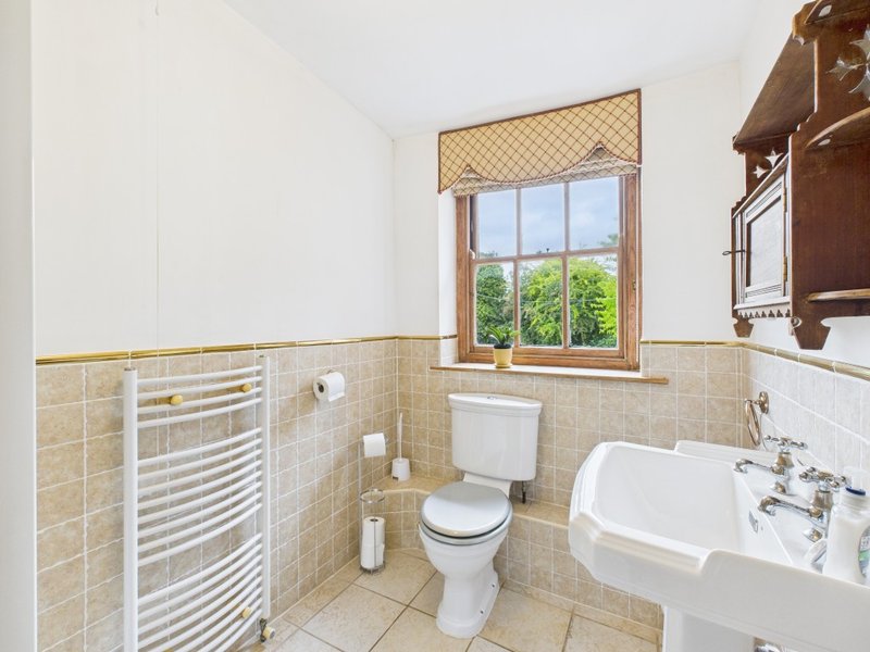 Bathroom with toilet, sink, towel rail, and window overlooking garden