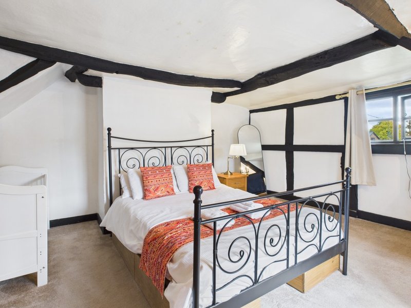 Bedroom with black wrought-iron bed frame, white bedding, orange decorative pillows and throw