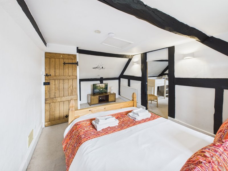 Bedroom with twin beds, wooden door, exposed dark beams and white walls