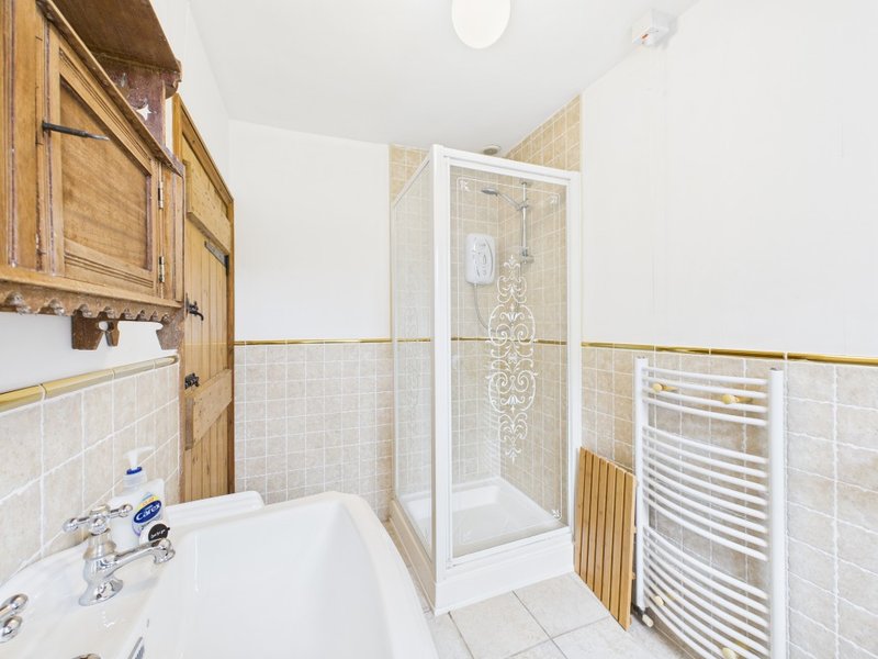 Bathroom with white sink, shower enclosure, wooden vanity cabinet and heated towel rail
