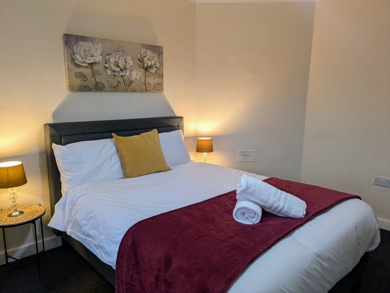 Comfortable double bedroom with fresh white linens, bedside tables and warm lighting.