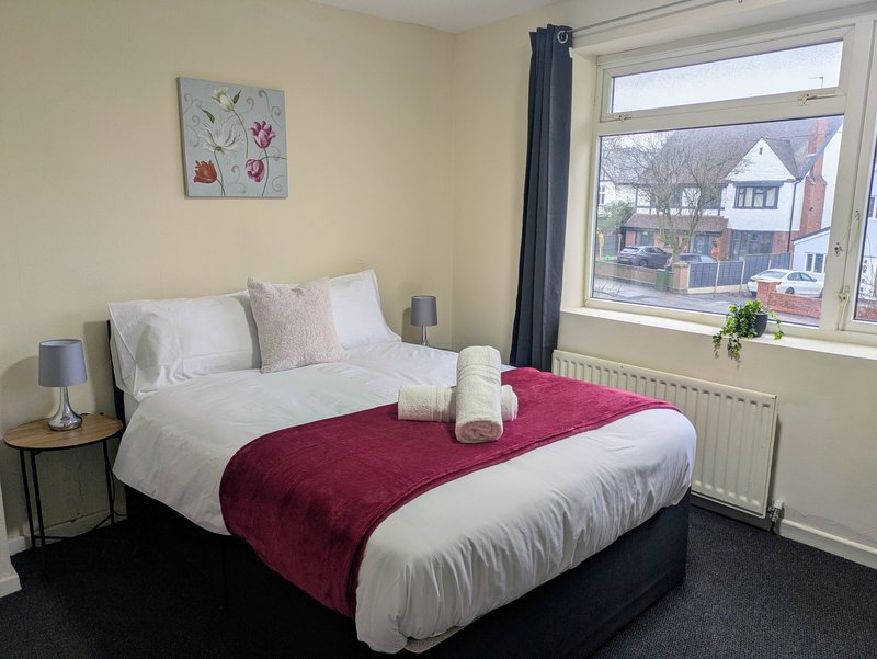 Spacious double bedroom ideal for working guests, with a large window providing plenty of natural light. A clean, welcoming space to relax and recharge after a busy working day.