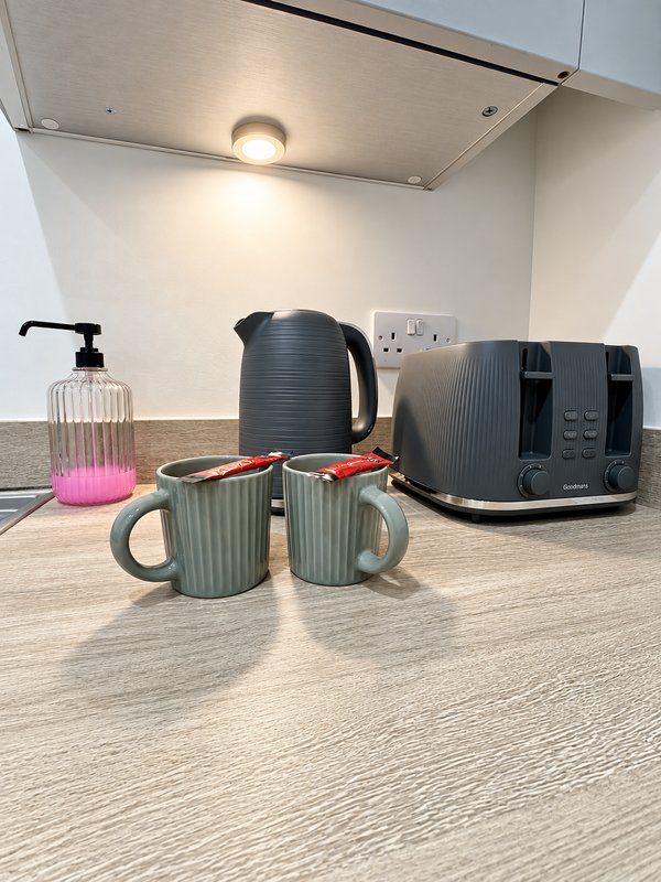 Kitchen counter with kettle, toaster, mugs and hand soap dispenser