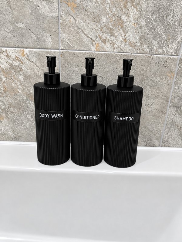 Bathroom shelf with three black pump bottles labeled body wash, conditioner, and shampoo