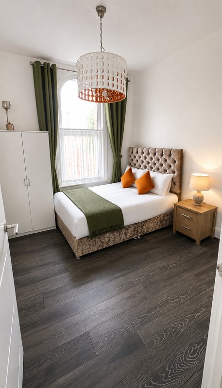 Bedroom with double bed, pendant light, green curtains, wooden nightstand and lamp