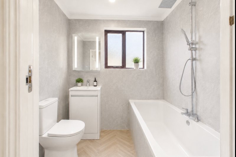 Modern bathroom with white toilet, vanity sink, illuminated mirror, bathtub and shower