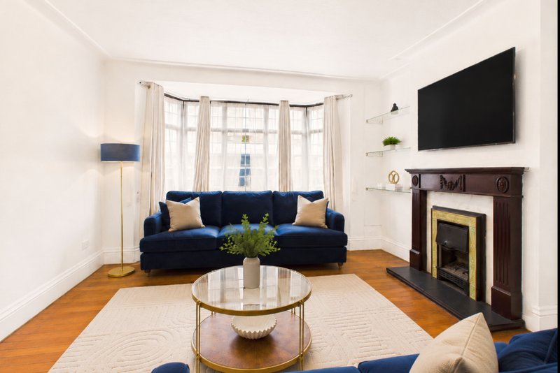 Bright living room with blue sofa, fireplace, bay window and wooden flooring