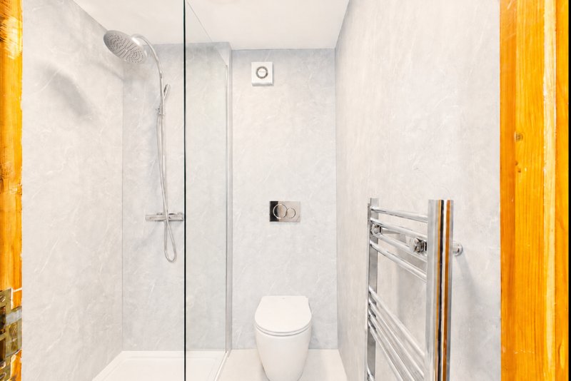 Modern bathroom with walk-in shower, toilet, heated towel rail and white tile walls
