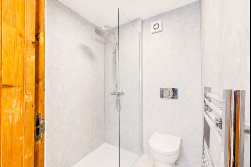 Modern bathroom with walk-in shower, toilet, heated towel rack and white tile walls