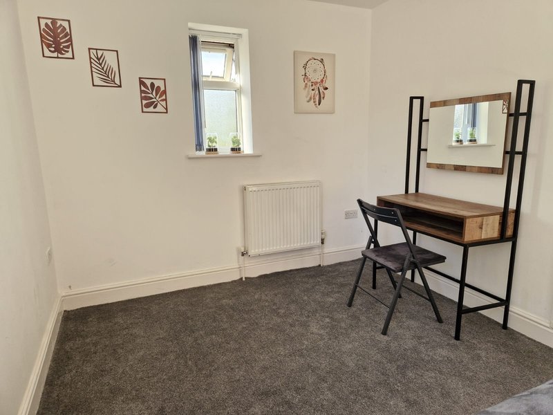 Bedroom with desk, chair, mirror, window, radiator and wall art