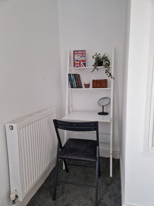 Small home office nook with white shelving, black chair, desk, potted plant and books