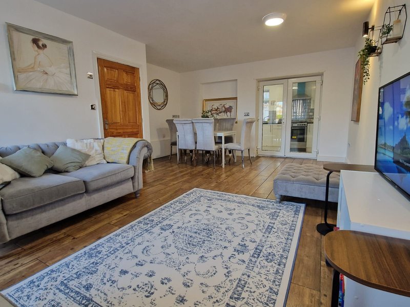 Open-plan living and dining room with sofa, dining table, wooden floors and television