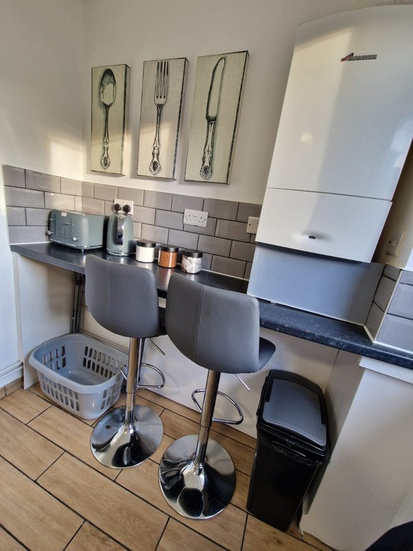 Kitchen with white boiler, subway tile backsplash, utensil wall art, and breakfast bar seating