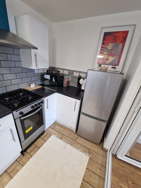 Modern kitchen with white cabinets, black countertop, gas stove, stainless steel fridge and subway tile backsplash
