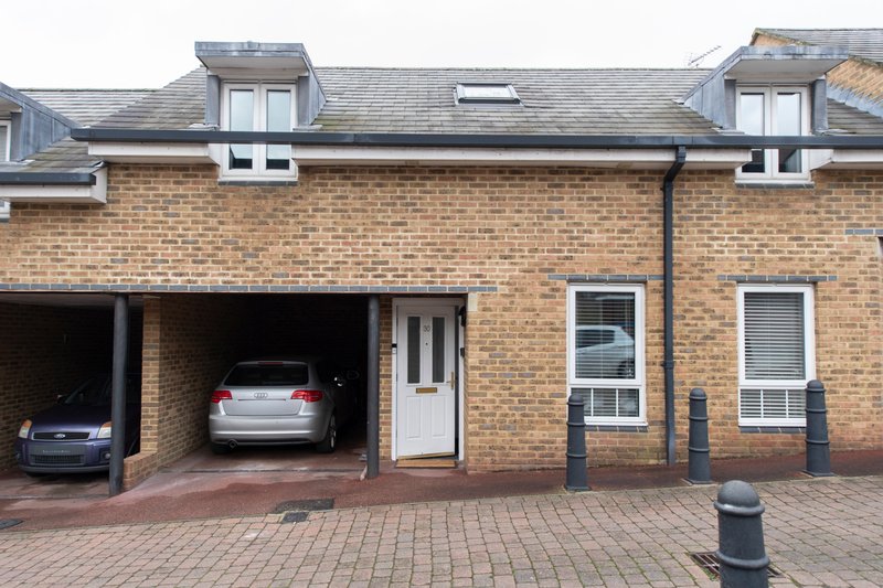 Brick townhouse exterior with driveway, garage, and front entrance door