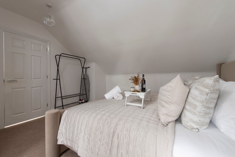 Bright bedroom with double bed, white bedding, decorative pillows and small nightstand
