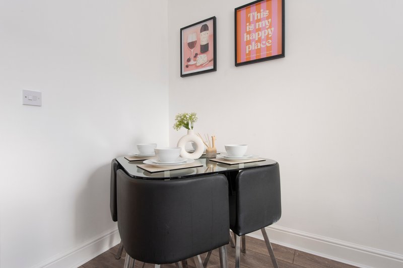 Dining nook with black table, upholstered chairs, place settings and wall art