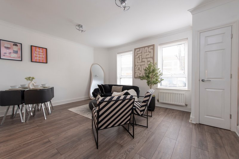 Modern living room with striped armchair, black side table, mirror and framed wall art
