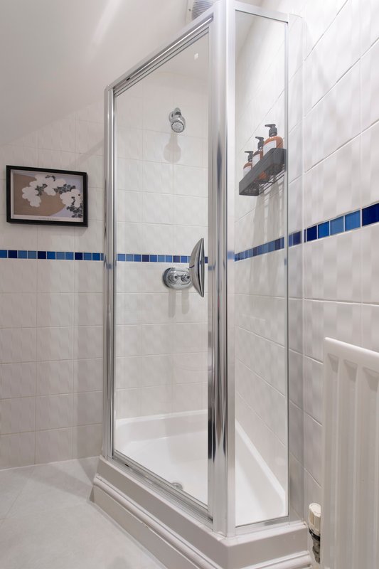 Modern bathroom with walk-in shower, glass enclosure, blue tile trim and framed artwork