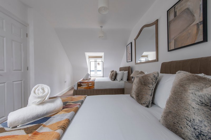 Twin bedroom with two beds, wooden floors, framed wall art, and natural light from window