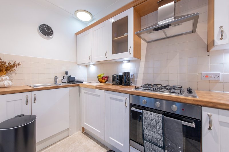 Modern kitchen with white cabinets, wooden worktops, gas hob and integrated oven