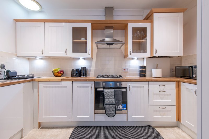 Modern kitchen with white cabinets, wooden countertops, gas hob and stainless steel hood