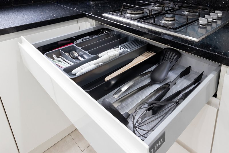 Open kitchen drawer with organized utensils, cutlery and kitchen tools